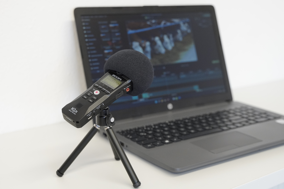 Ein aufgeklappter Laptop, vor dem ein Mikrofon steht.