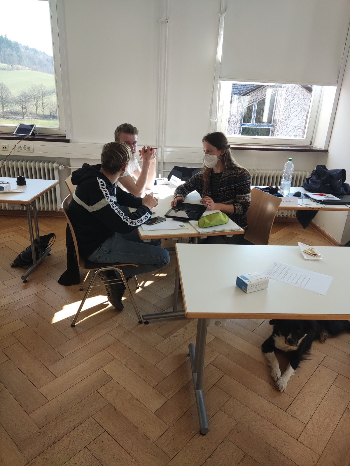 Drei Schülerinnen und Schüler, die gemeinsam am IPad arbeiten.